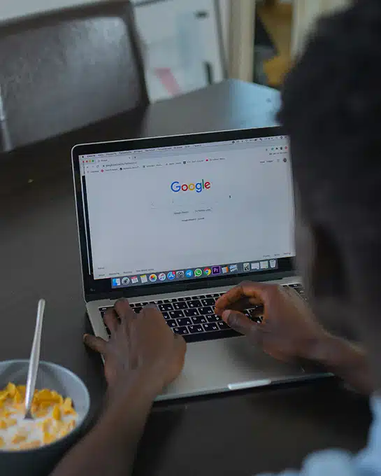 Person searching Google for SEO for dentists and local dental services on a laptop during breakfast in Dallas Fort Worth