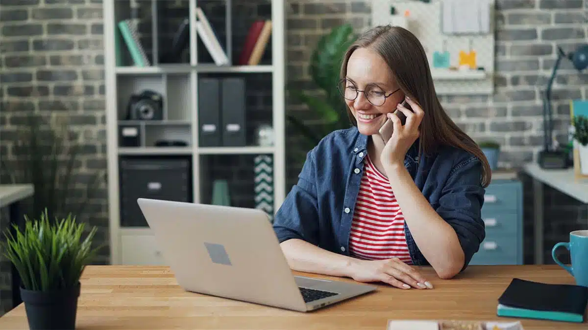 Business professional using a laptop and smartphone in a modern office for digital marketing work